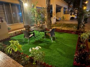 um pátio com uma mesa e cadeiras sobre relva verde em Holidazzle Villa em Karachi