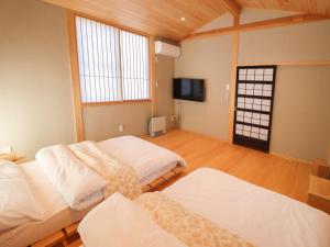 een kamer met 2 bedden en een flatscreen-tv bij 会津若松 A-UN lNN 人気観光地へ車で10分 in Aizuwakamatsu