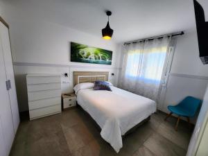 um quarto com uma cama e uma cadeira azul em Apartamentos Playa De Covachos em Soto de la Marina