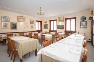 une salle à manger avec des tables blanches, des chaises et des fenêtres dans l'établissement Il Grifo, à Lenno