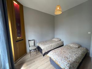 2 camas en una habitación con silla y puerta en ALTA, en Bourg-lès-Valence