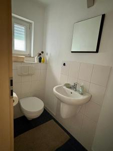 een witte badkamer met een toilet en een wastafel bij Ferienwohnung am Wartturm in Besigheim