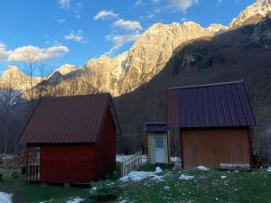 un granero rojo con montañas al fondo en Bujtina Diti, en Tropojë