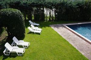 - un groupe de chaises blanches installées à côté de la piscine dans l'établissement Hotel Diana, à Riva del Garda