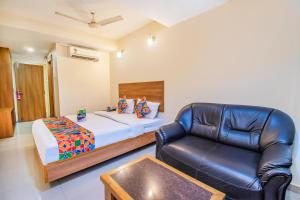 een slaapkamer met een bed en een leren stoel bij FabHotel Jansi Deluxe - Nr Gandhipuram Bus stand in Coimbatore