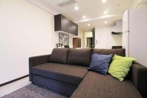 ein Wohnzimmer mit einem braunen Sofa und bunten Kissen in der Unterkunft bHOTEL La-Shante - 5 mins walk to the PeacePark & 2BR 10 ppl #101 in Hiroshima