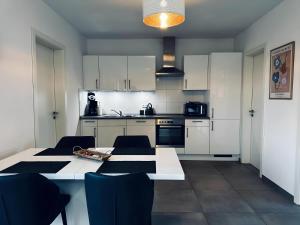 a kitchen with white cabinets and a table and chairs at FeWo Am Povelturm - mit Aufzug und großer Loggia in Nordhorn