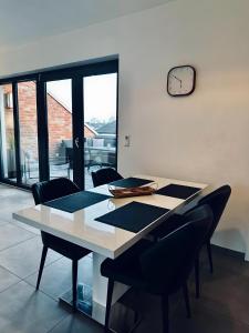 a dining room table with chairs and a clock on the wall at FeWo Am Povelturm - mit Aufzug und großer Loggia in Nordhorn