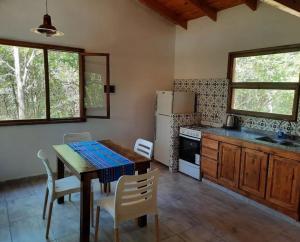 uma cozinha com uma mesa e cadeiras e um frigorífico em Las Casitas de Piedra I em Villa General Belgrano