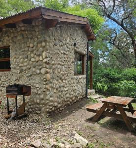 um edifício de pedra com uma mesa de piquenique e um banco em Las Casitas de Piedra I em Villa General Belgrano