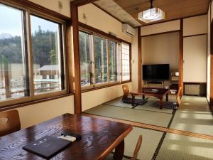 een kamer met een tafel, een tv en een aantal ramen bij 大和屋ホテルいろは in Nikko