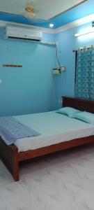 Bett in einem Zimmer mit blauer Wand in der Unterkunft Centaurus Homestay near Trichy Airport in Tiruchchirāppalli