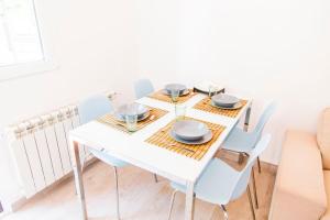 - une table à manger blanche avec des chaises blanches, des assiettes et des verres dans l'établissement Céntrico apartamento bien ubicado para 5, 3 Hab, à Alcobendas