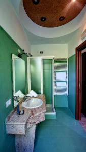 Baño verde con lavabo y espejo en Botanique Hotel Vergani, en Fara Gera dʼAdda