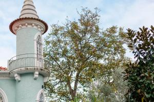 ein blaues Gebäude mit einem Turm und einem Baum in der Unterkunft Torres da Vila in Anadia