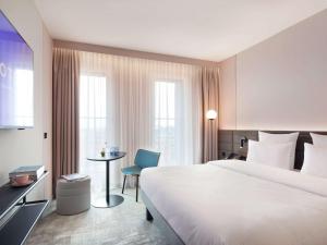 Novotel Hamburg Central Station في هامبورغ: غرفة الفندق بسرير ابيض كبير وطاولة