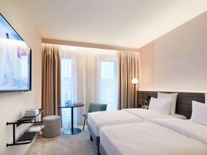 Novotel Hamburg Central Station في هامبورغ: غرفة فندقية بسريرين وطاولة