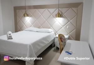 Hotel Valledupar Plaza في فاليدوبار: غرفة نوم بسرير ابيض وطاولة