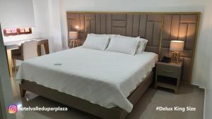 Hotel Valledupar Plaza في فاليدوبار: غرفة نوم مع سرير أبيض كبير ومكتب