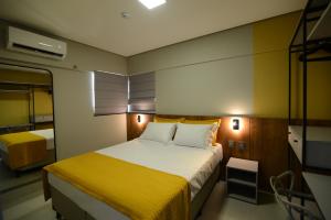 um pequeno quarto com uma cama com um cobertor amarelo em Brisas Flat Style em Cuiabá