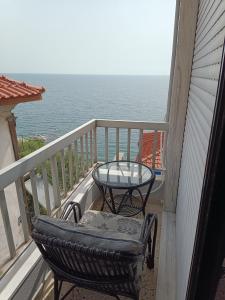 een tafel en stoelen op een balkon met uitzicht op de oceaan bij Kalys House in Kavala