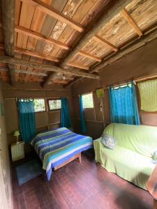 1 Schlafzimmer mit 2 Betten und blauen Vorhängen in der Unterkunft Eco habitación en Tierra Fértil Eco Posada in Santa Ana