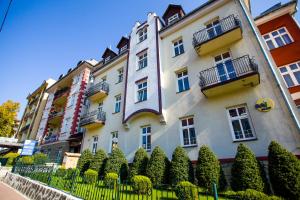 un grande edificio bianco con cespugli di fronte di Hotel *** NAT Krynica Zdrój a Krynica-Zdrój