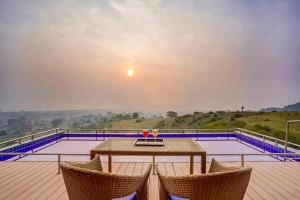 un tavolo e due sedie su una terrazza con piscina di Wabi Sabi Resort, Igatpuri a Igatpuri