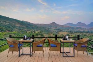 un tavolo e sedie su una terrazza con vista sulle montagne di Wabi Sabi Resort, Igatpuri a Igatpuri