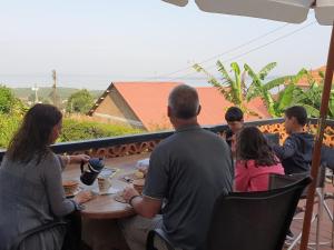 um grupo de pessoas sentadas em torno de uma mesa em um pátio em Alison & Dave's Guesthouse em Entebbe