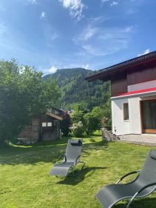 ツェル・アム・ゼーにあるChalet Panoramablick Zell am Seeの家の横の芝生に座る椅子2脚