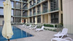 um hotel com cadeiras e uma piscina em frente a um edifício em Valentina Studio Transit Apartment in Masdar City em Abu Dhabi