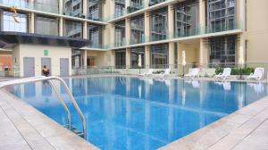 uma grande piscina num edifício com cadeiras em Valentina Studio Transit Apartment in Masdar City em Abu Dhabi