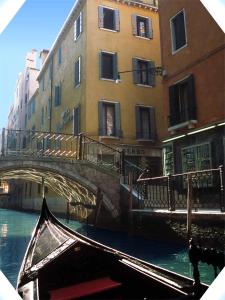 uma gôndola que passa debaixo de uma ponte sobre um canal em Albergo San Marco em Veneza