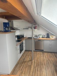 una cucina mansardata con armadi bianchi e pavimenti in legno di Ferienwohnung Niederrotweil a Niederrotweil