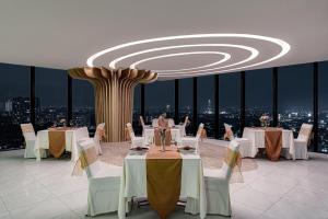 スラバヤにあるWhiz Luxe Hotel Spazio Surabayaのダイニングルーム(テーブル、椅子付)