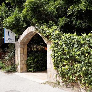 een stenen boog met een groene heg bij Cirali Hotel in Cıralı