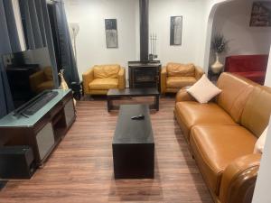 a living room with a couch and a tv and chairs at Newly Renovated House near Melbourne Airport in Melbourne