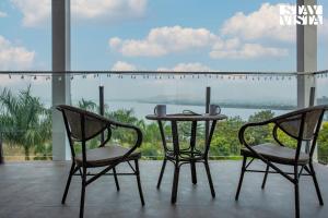 twee stoelen en een tafel voor een raam bij StayVista's Del Lago Farms - Lakeview Villa with Infinity Pool, Projector & Indoor-Outdoor Games in Nashik