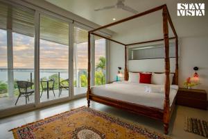 een slaapkamer met een hemelbed en een balkon bij StayVista's Del Lago Farms - Lakeview Villa with Infinity Pool, Projector & Indoor-Outdoor Games in Nashik