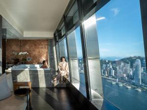 een vrouw aan een tafel in een kamer met uitzicht bij The Ritz-Carlton, Hong Kong in Hong Kong