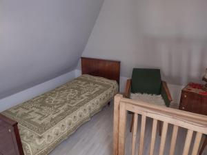 ein kleines Schlafzimmer mit einem Bett und einem Stuhl in der Unterkunft Loft 'PRL' in Tykocin