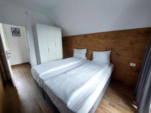 una camera da letto con un grande letto bianco con testiera in legno di Orange Villa with private pool a Ilidža