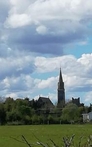 een kerk met een toren in een groen veld bij PatsView Lodge in Donegal