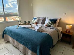 een slaapkamer met een groot bed en een blauwe deken bij Studio 1131 - Extraordinário in Ribeirão Preto