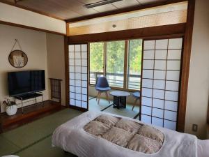 een slaapkamer met een bed, een tv en ramen bij 大和屋ホテルいろは in Nikko