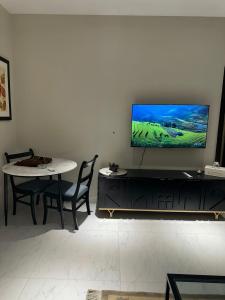 a living room with a table and a tv on a wall at The Opus Luxury Residences in Lahore