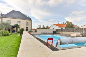 una piscina con sedia rossa accanto a una casa di Maison Marie Barrault a Les Herbiers