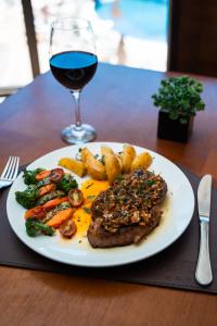 un piatto di carne e verdure con un bicchiere di vino di Foz Plaza Hotel a Foz do Iguaçu