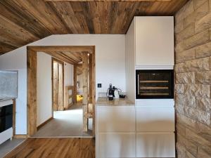 a kitchen with white cabinets and a stone wall at Magnifique attique avec vue sur le lac de la Moubra in Crans-Montana